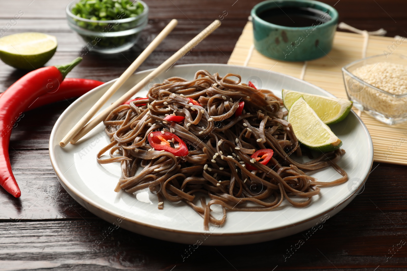 Photo of Tasty buckwheat noodles (soba) with chili pepper served on wooden table, closeup