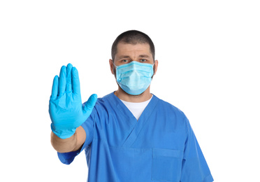 Photo of Doctor in protective mask showing stop gesture on white background. Prevent spreading of coronavirus