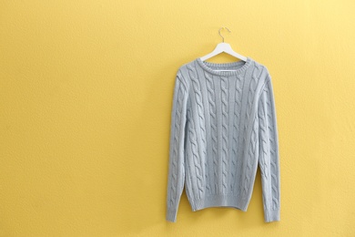 Photo of Hanger with stylish sweater on yellow wall. Space for text