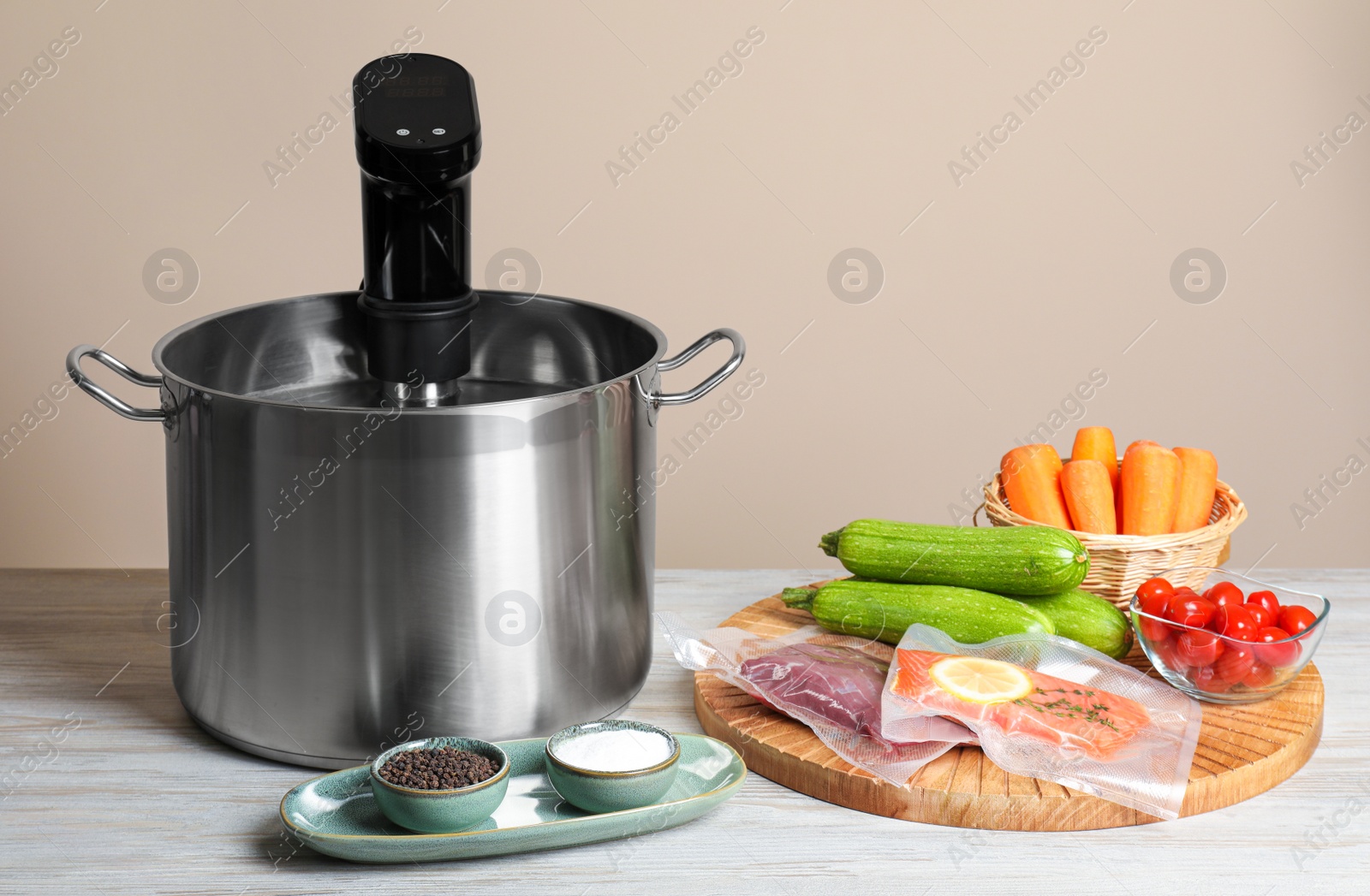 Photo of Thermal immersion circulator in pot and ingredients on white wooden table. Vacuum packing for sous vide cooking