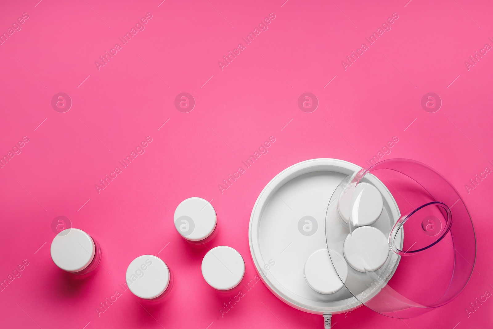 Photo of Modern yogurt maker with jars on pink background, flat lay. Space for text