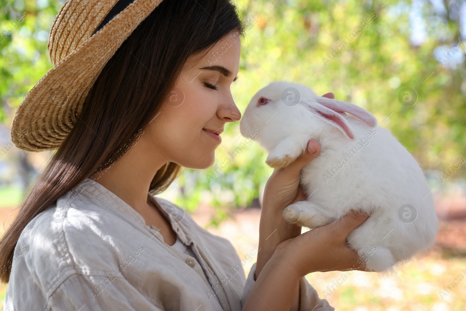 Photo of Happy woman holding cute white rabbit in park