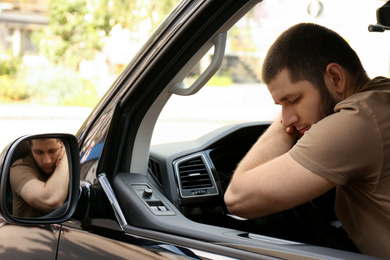 Photo of Tired man sleeping on steering wheel in his car