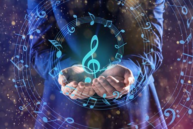 Image of Musician holding staff with music notes and symbols on color background, closeup