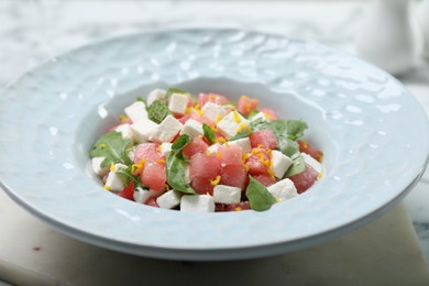 Photo of Delicious salad with watermelon, arugula and feta cheese served on white marble table, closeup