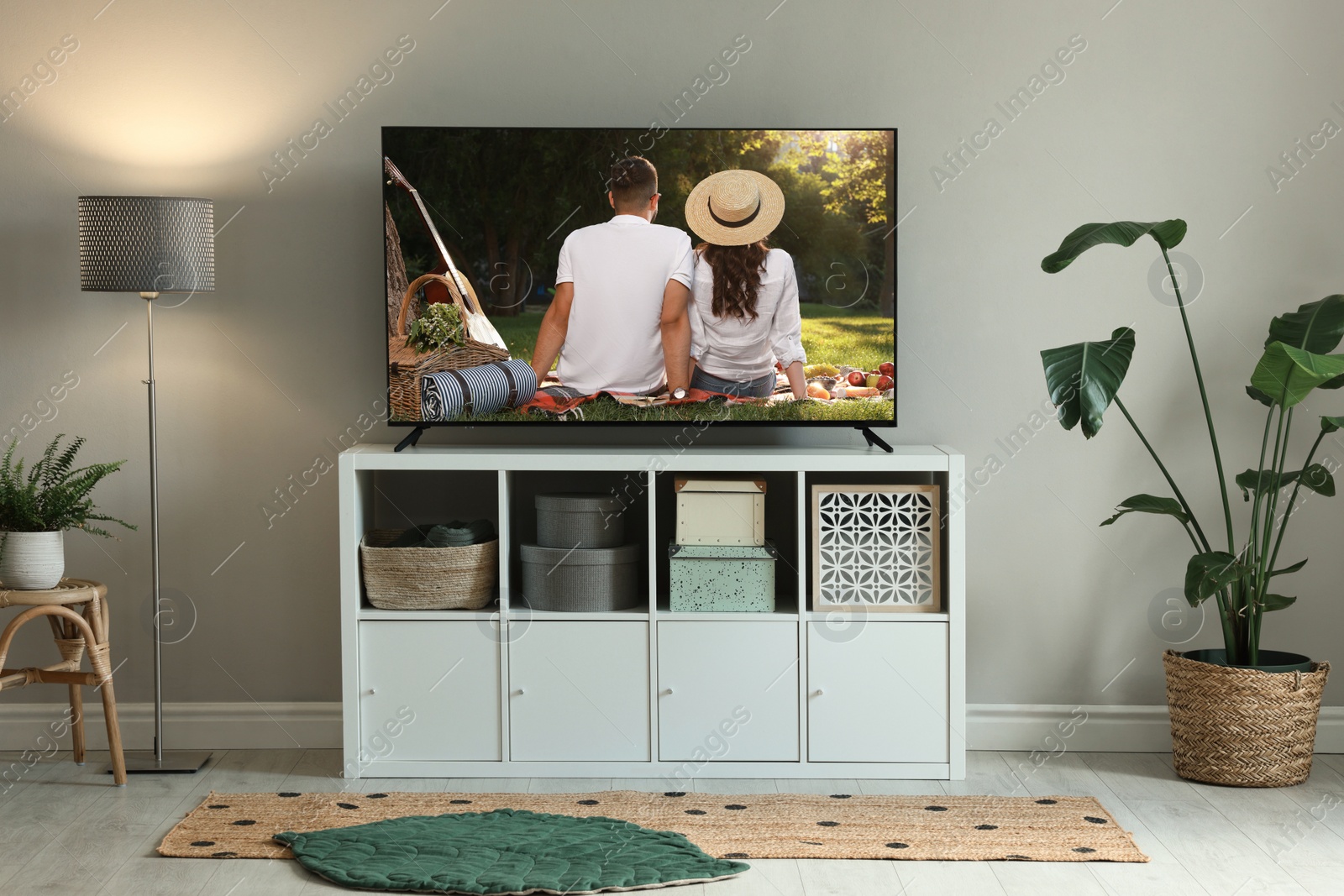 Image of Modern TV set on wooden stand in room. Scene of romantic movie on screen