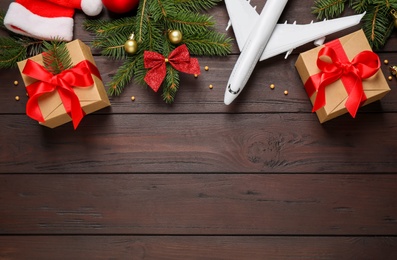 Photo of Flat lay composition with Christmas decorations and toy airplane on wooden background, space for text. Winter vacation