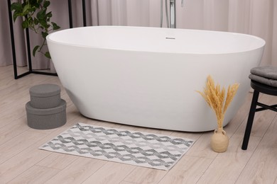 Stylish bathroom interior with soft bath mat and tub