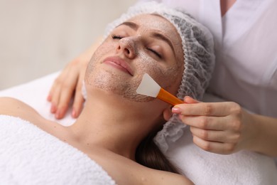 Photo of Cosmetologist applying mask on woman's face in clinic, closeup