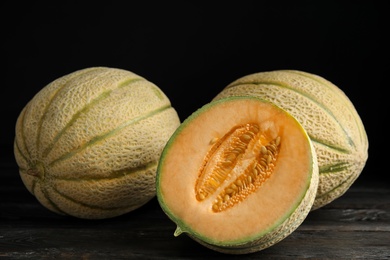 Tasty fresh melons on black wooden table, closeup