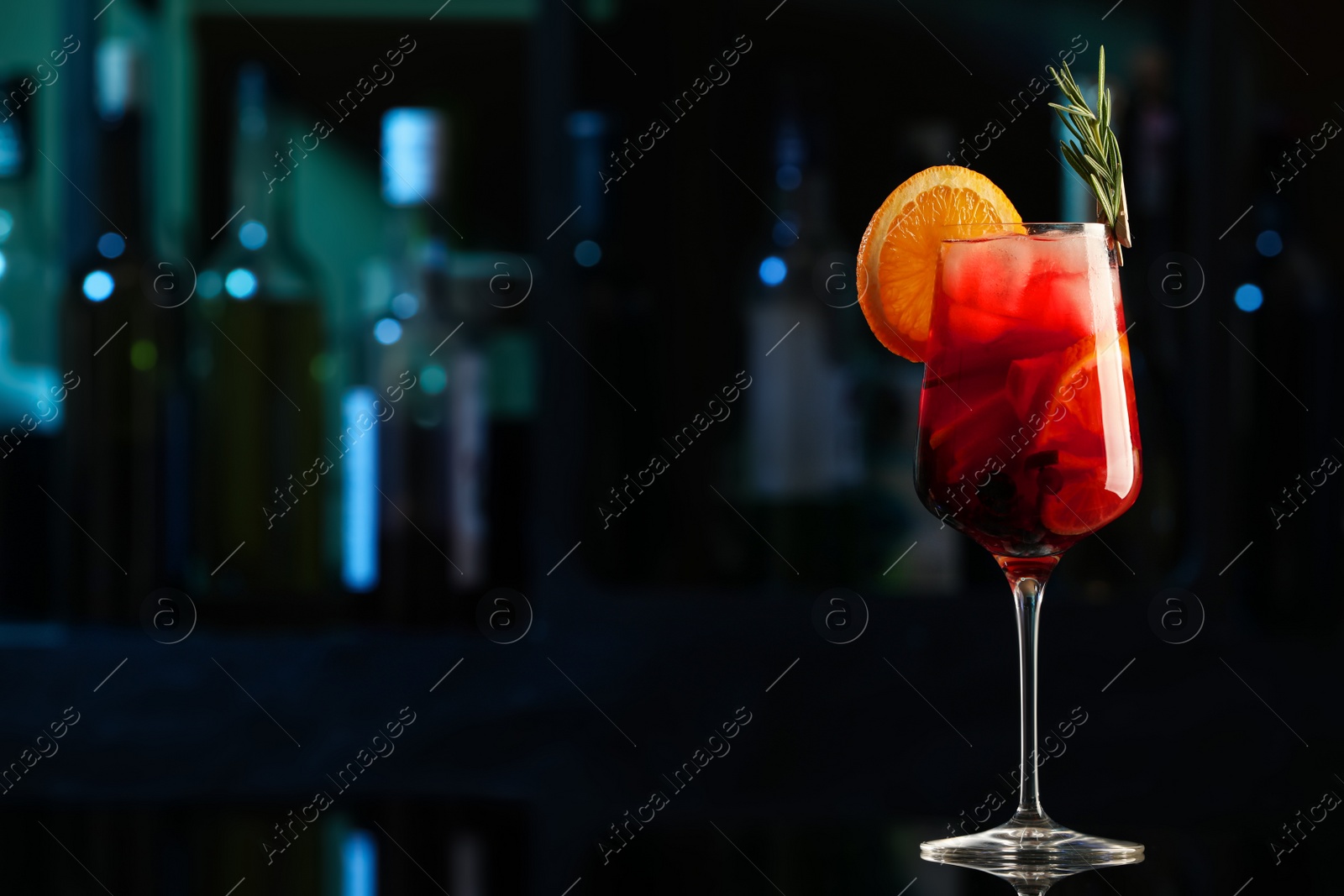 Photo of Delicious sangria cocktail on black table in bar. Space for text