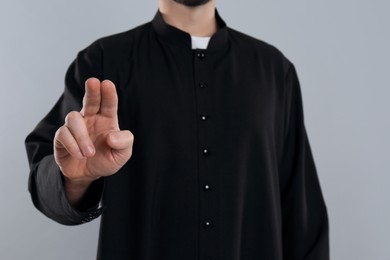 Photo of Priest making blessing gesture on grey background, closeup