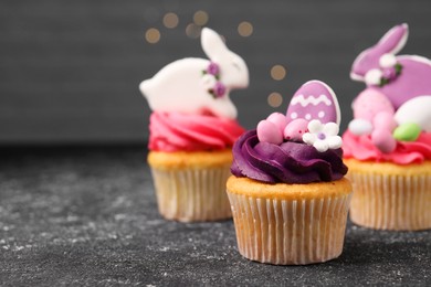 Photo of Tasty decorated Easter cupcakes on grey table, space for text