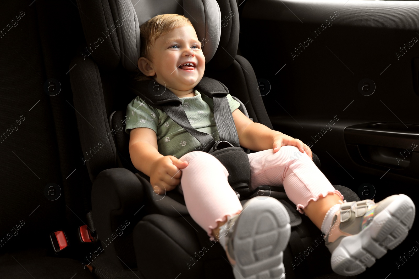 Photo of Cute little girl sitting in child safety seat inside car