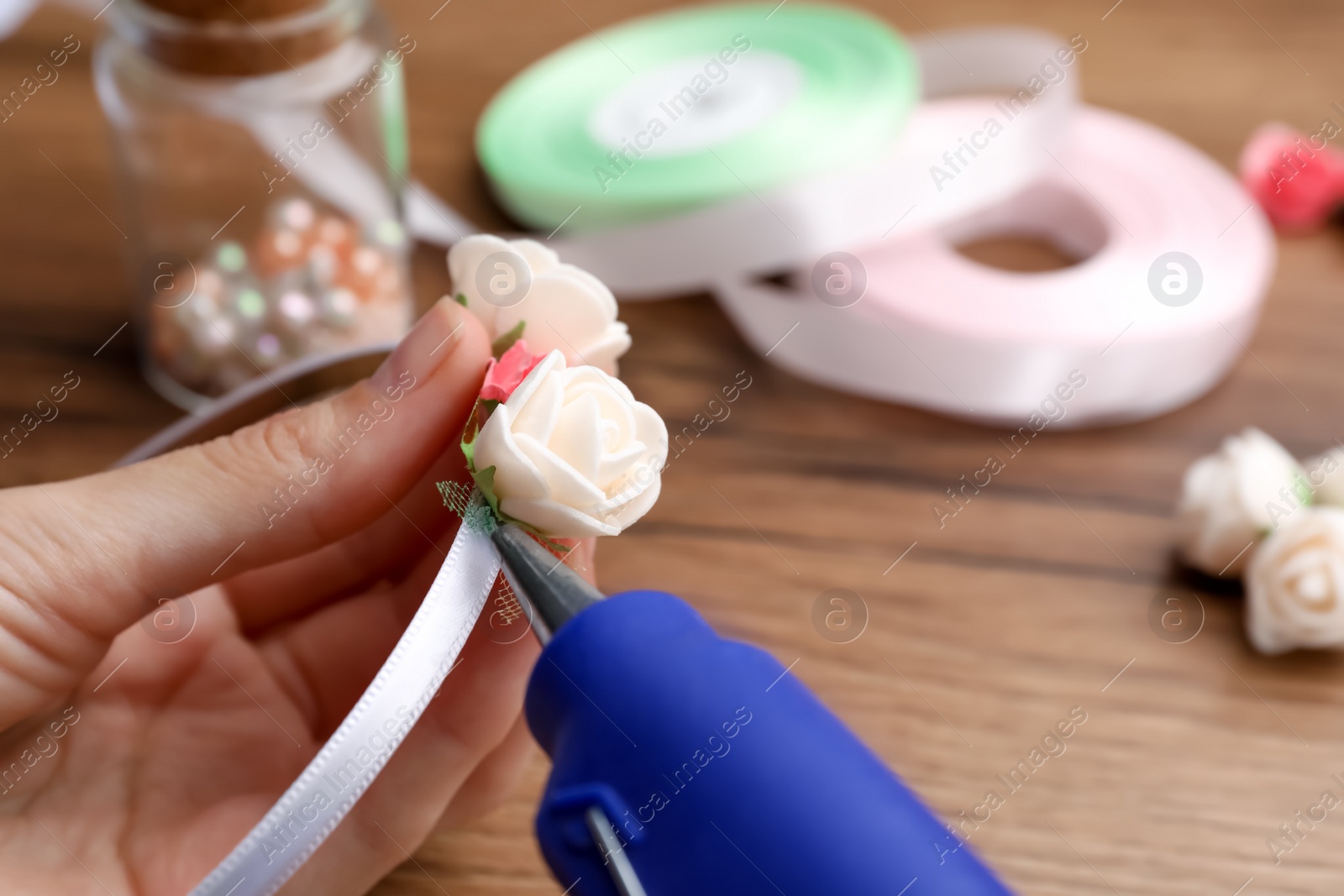 Photo of Woman with hot glue gun making craft at wooden table, closeup