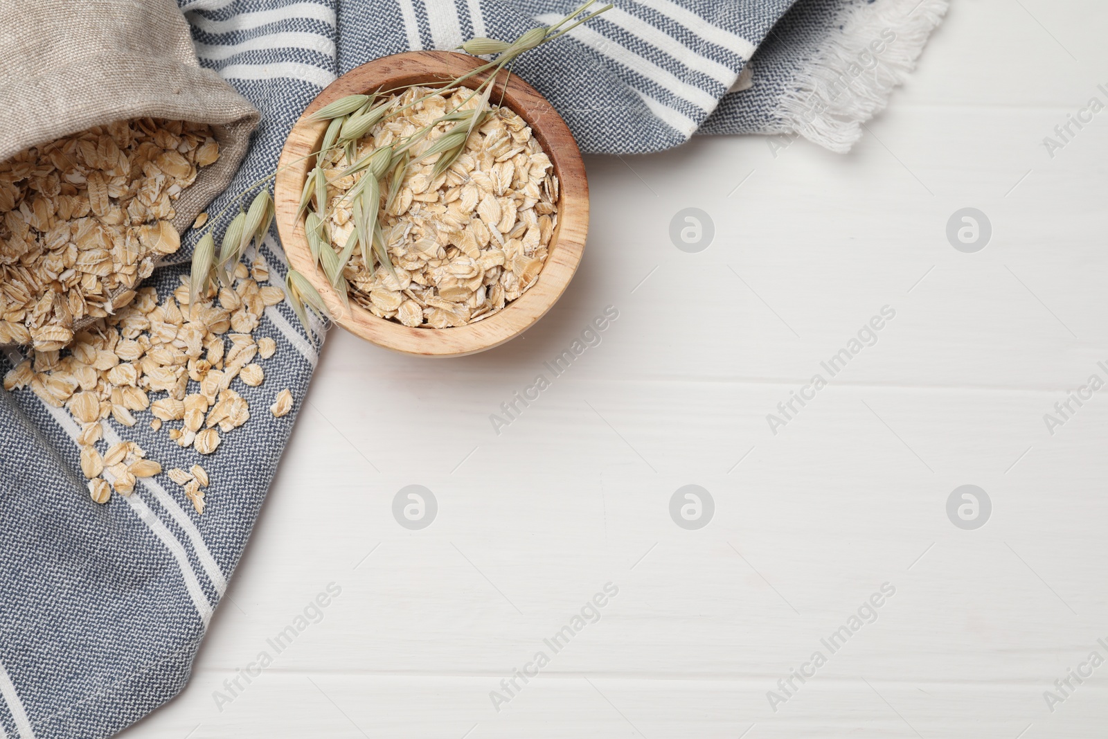 Photo of Oatmeal and florets on white wooden table, flat lay. Space for text