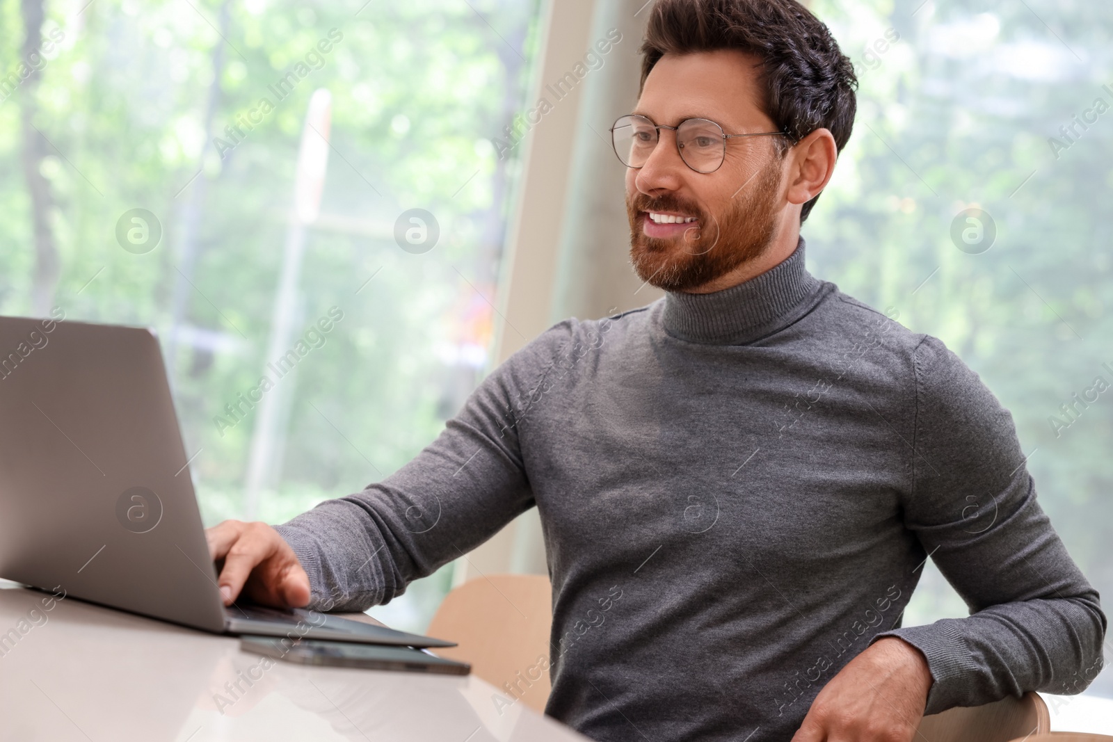 Photo of Man working on laptop at table in cafe