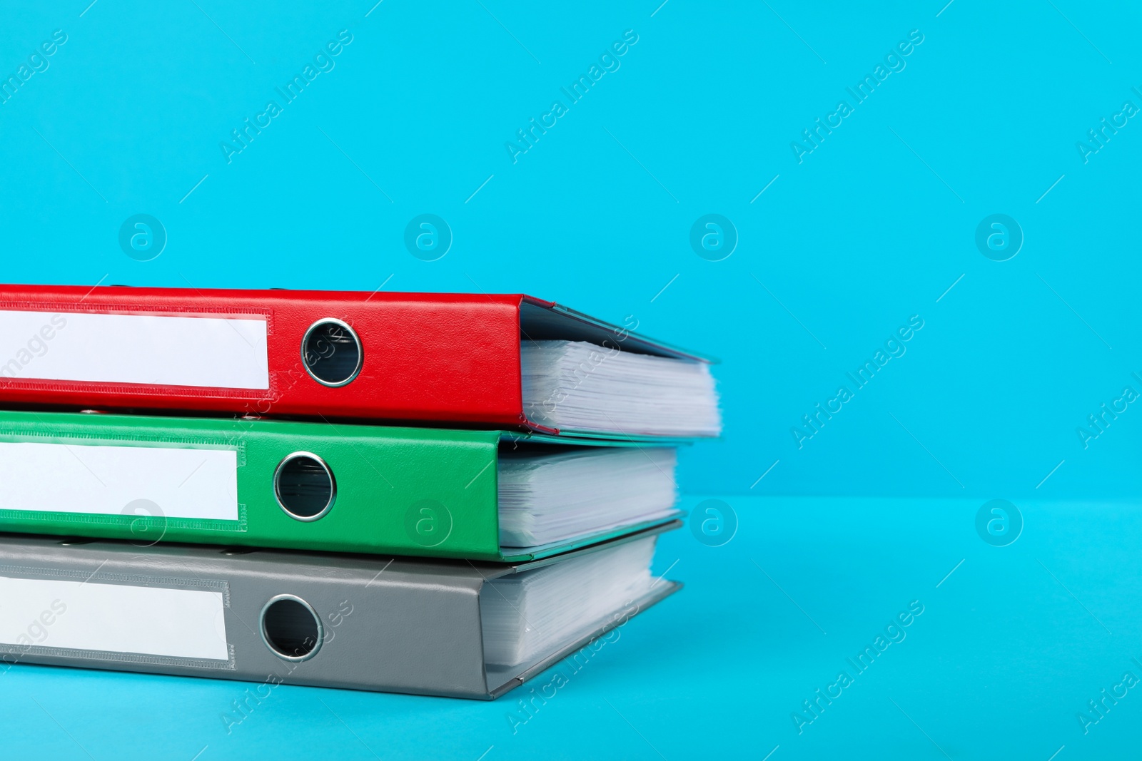 Photo of Stack of office folders on light blue background, space for text