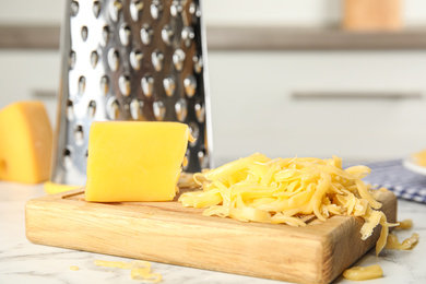 Photo of Delicious grated cheese on white marble table in kitchen