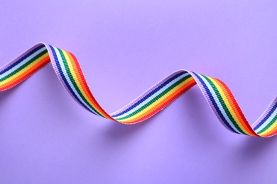 Photo of Bright rainbow ribbon on color background, top view. Symbol of gay community
