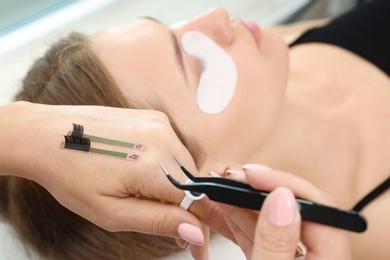 Photo of Beautician preparing for eyelash extensions procedure, closeup