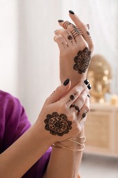 Photo of Woman with henna tattoos on hands indoors, closeup. Traditional mehndi ornament