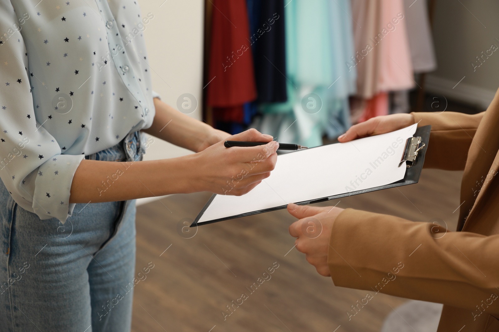 Photo of Woman signing rental agreement in clothing salon, closeup