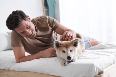 Man and adorable Akita Inu dog in bedroom