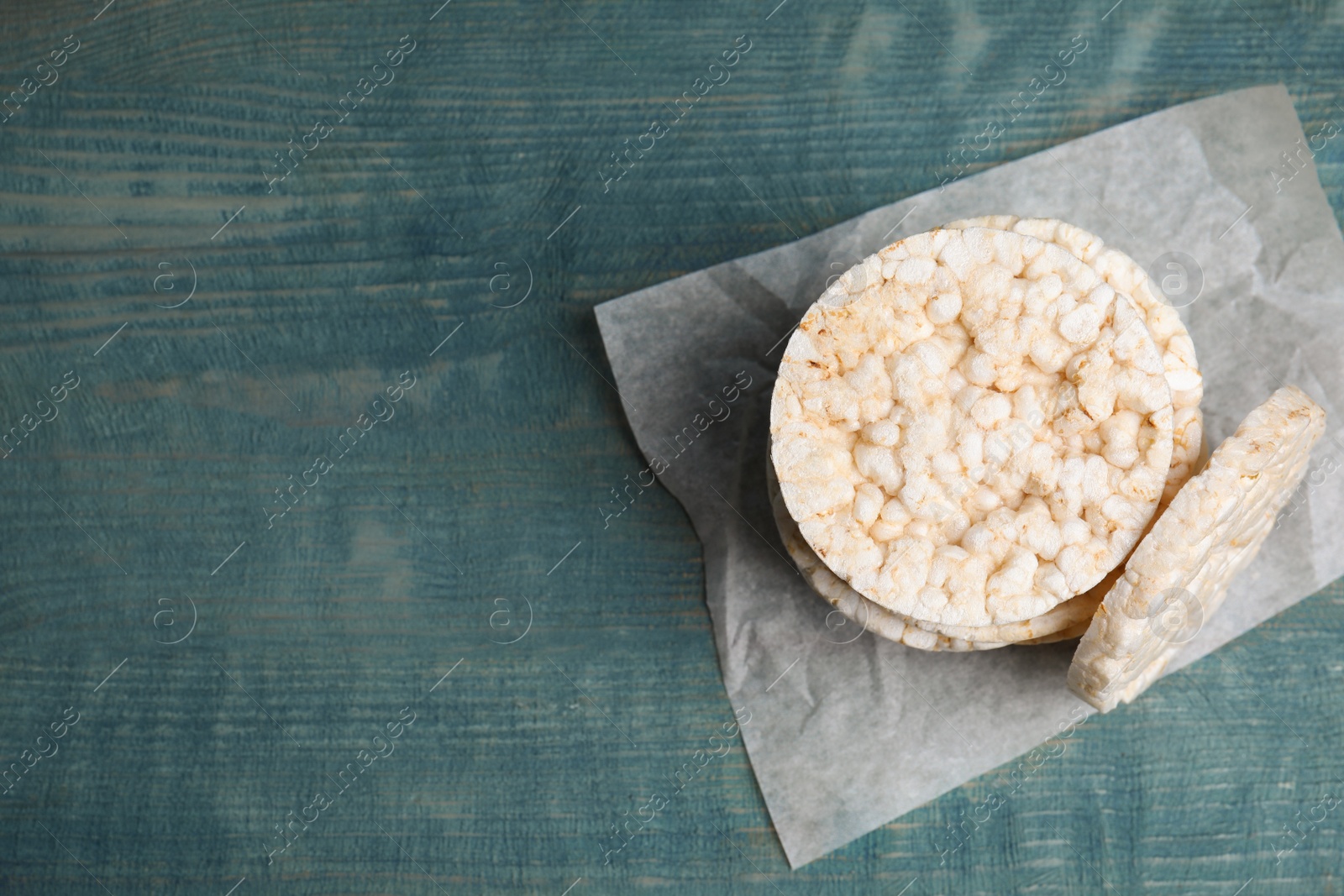 Photo of Stack of crunchy rice cakes on light blue wooden table, top view. Space for text