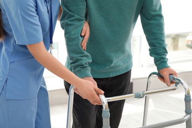 Photo of Nurse assisting senior man with walker in hospital, closeup