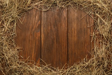 Photo of Frame made of dried hay on wooden background, top view. Space for text