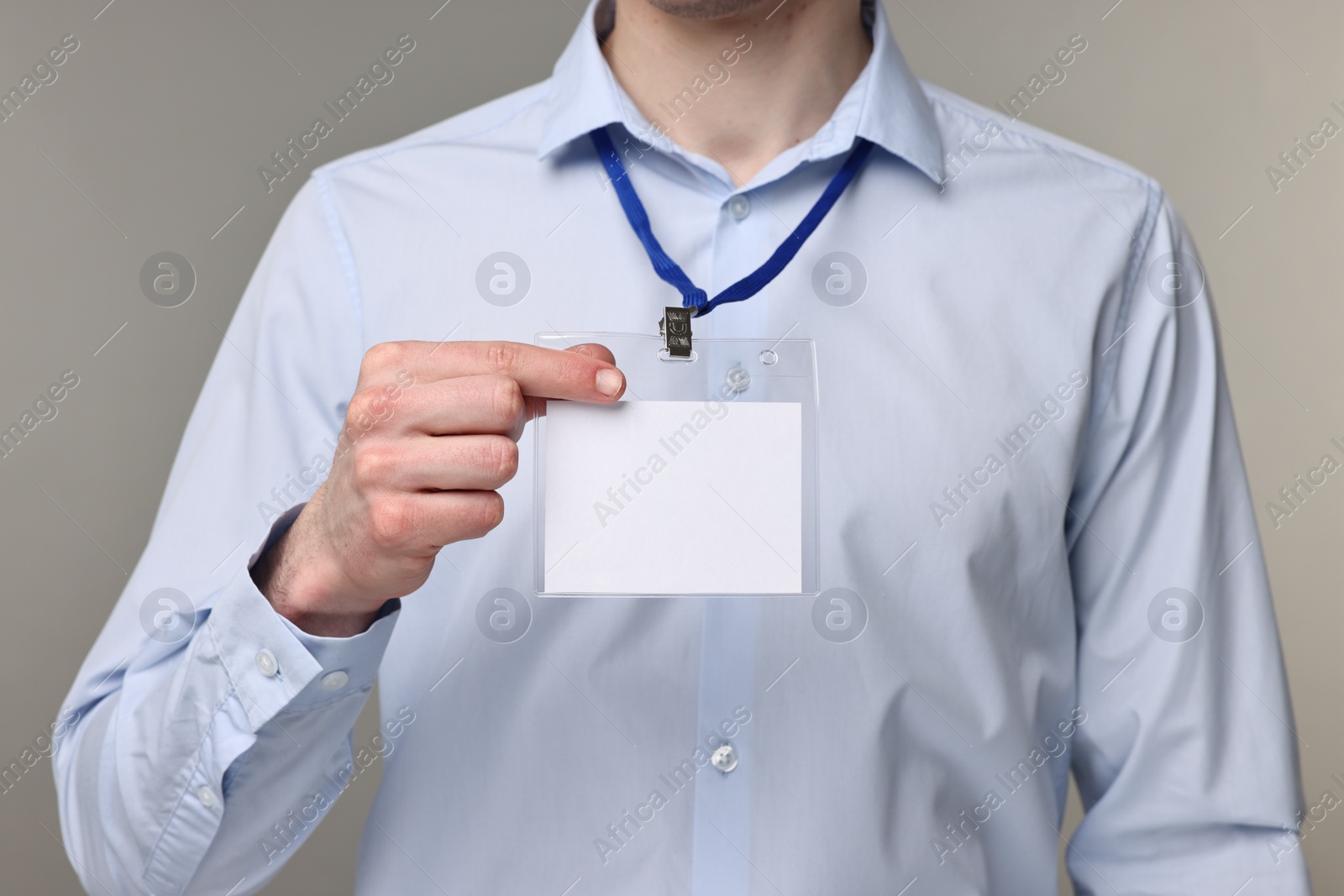 Photo of Man showing empty badge on grey background, closeup