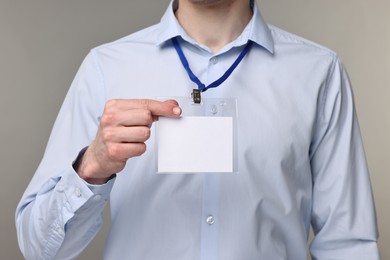 Photo of Man showing empty badge on grey background, closeup