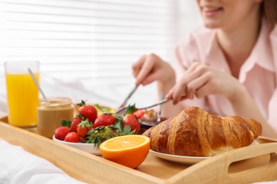 Photo of Smiling woman having tasty breakfast on bed, closeup