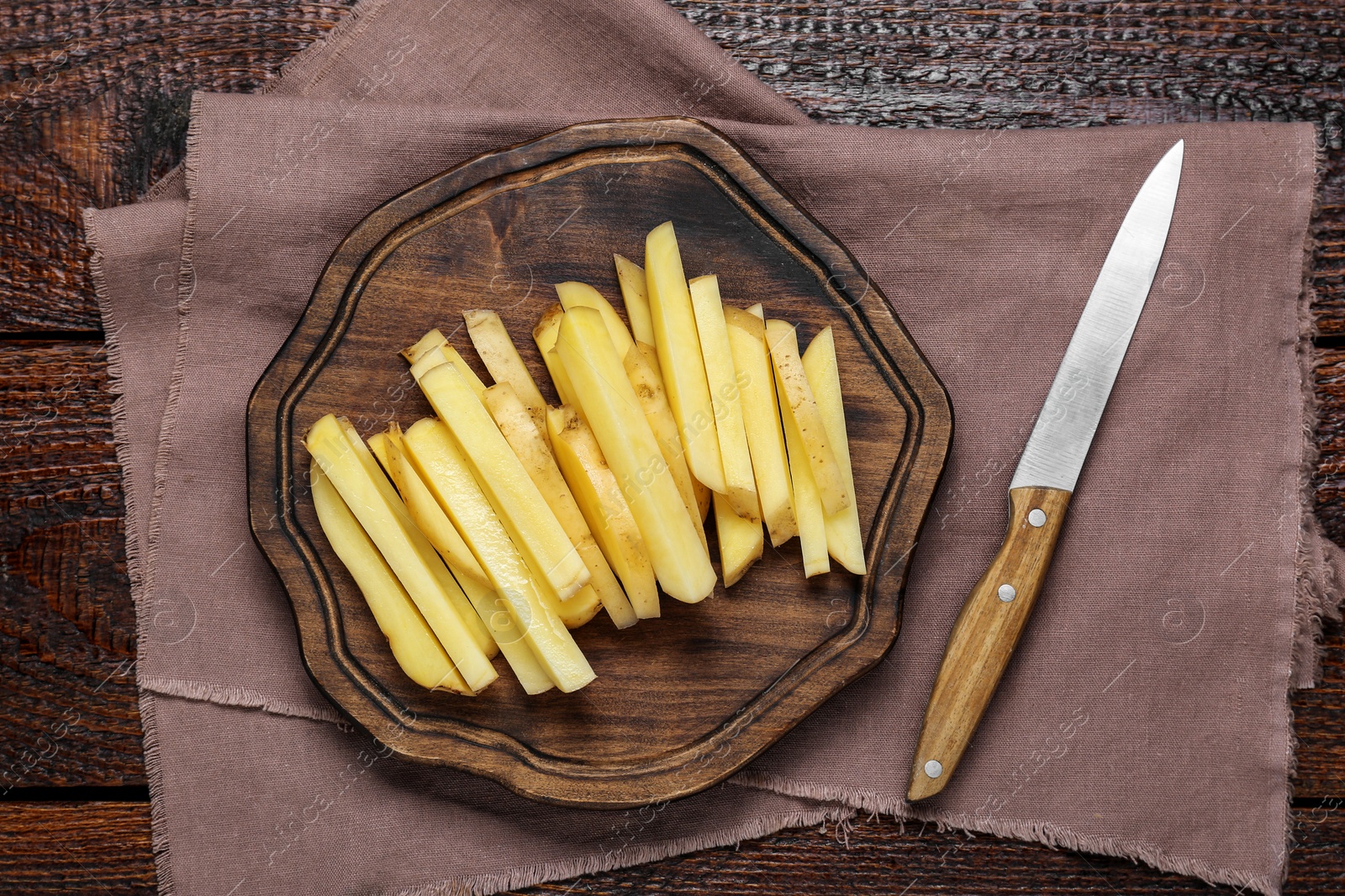 Photo of Cut raw potatoes and knife on wooden table, top view