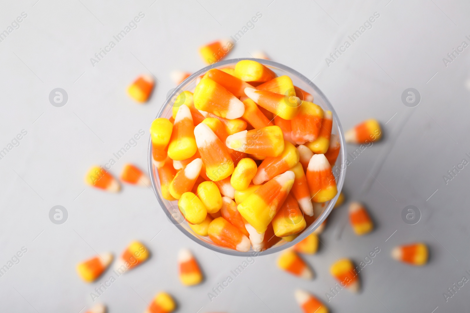 Photo of Glass of tasty candy corns on gray background, top view