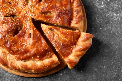 Photo of Cut delicious homemade pie on black table, top view. Space for text