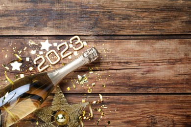 Photo of Happy New Year 2023! Flat lay composition with bottle of sparkling wine on wooden table, space for text