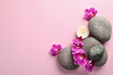 Flat lay composition with spa stones and orchid flowers on pink background. Space for text