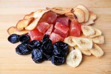 Photo of Pile of different tasty dried fruits on wooden table, closeup