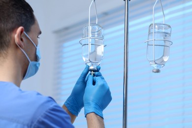 Nurse setting up IV drip in hospital, selective focus