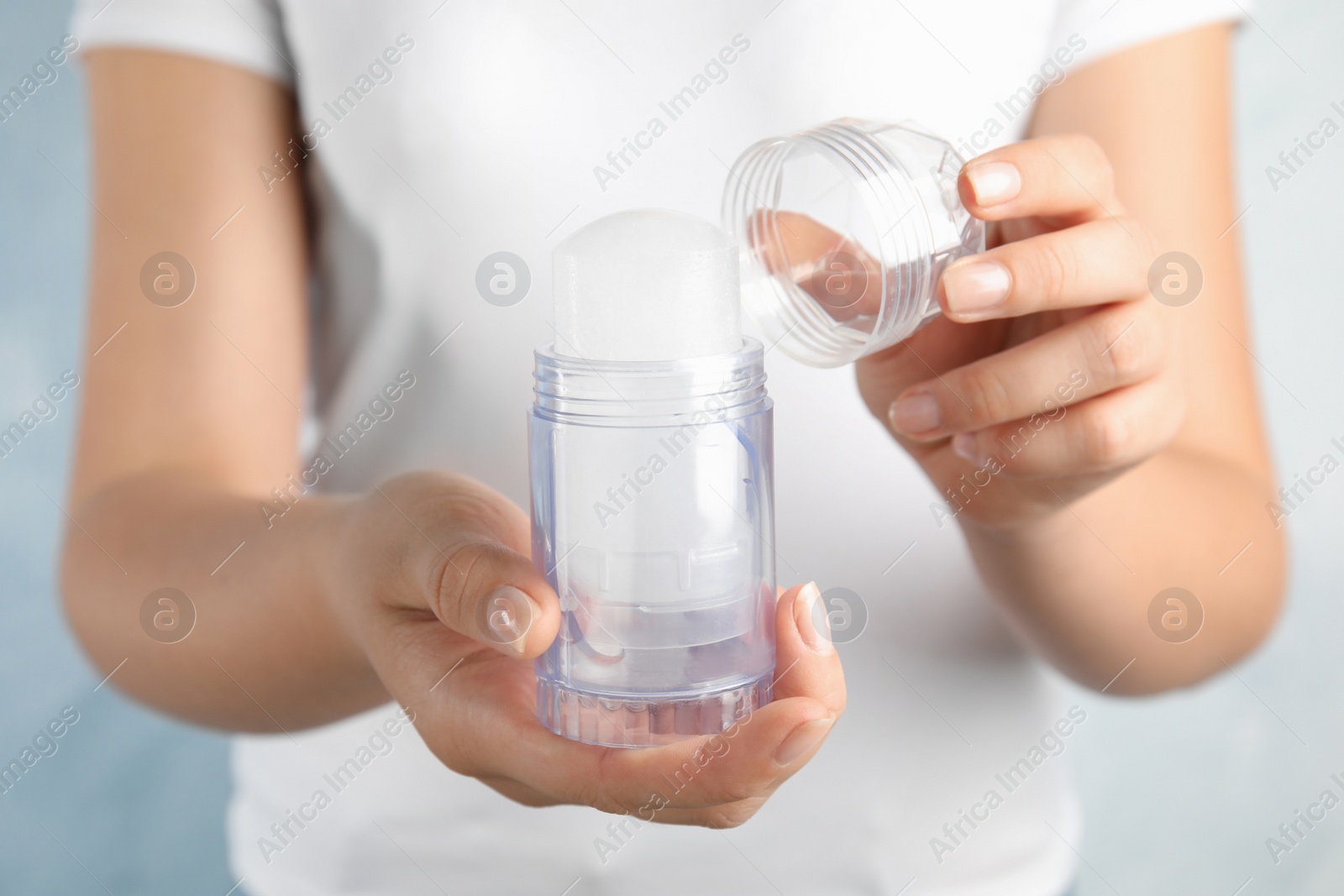 Photo of Young woman holding natural crystal alum stick deodorant, closeup