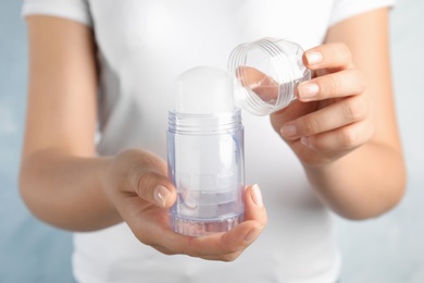 Photo of Young woman holding natural crystal alum stick deodorant, closeup