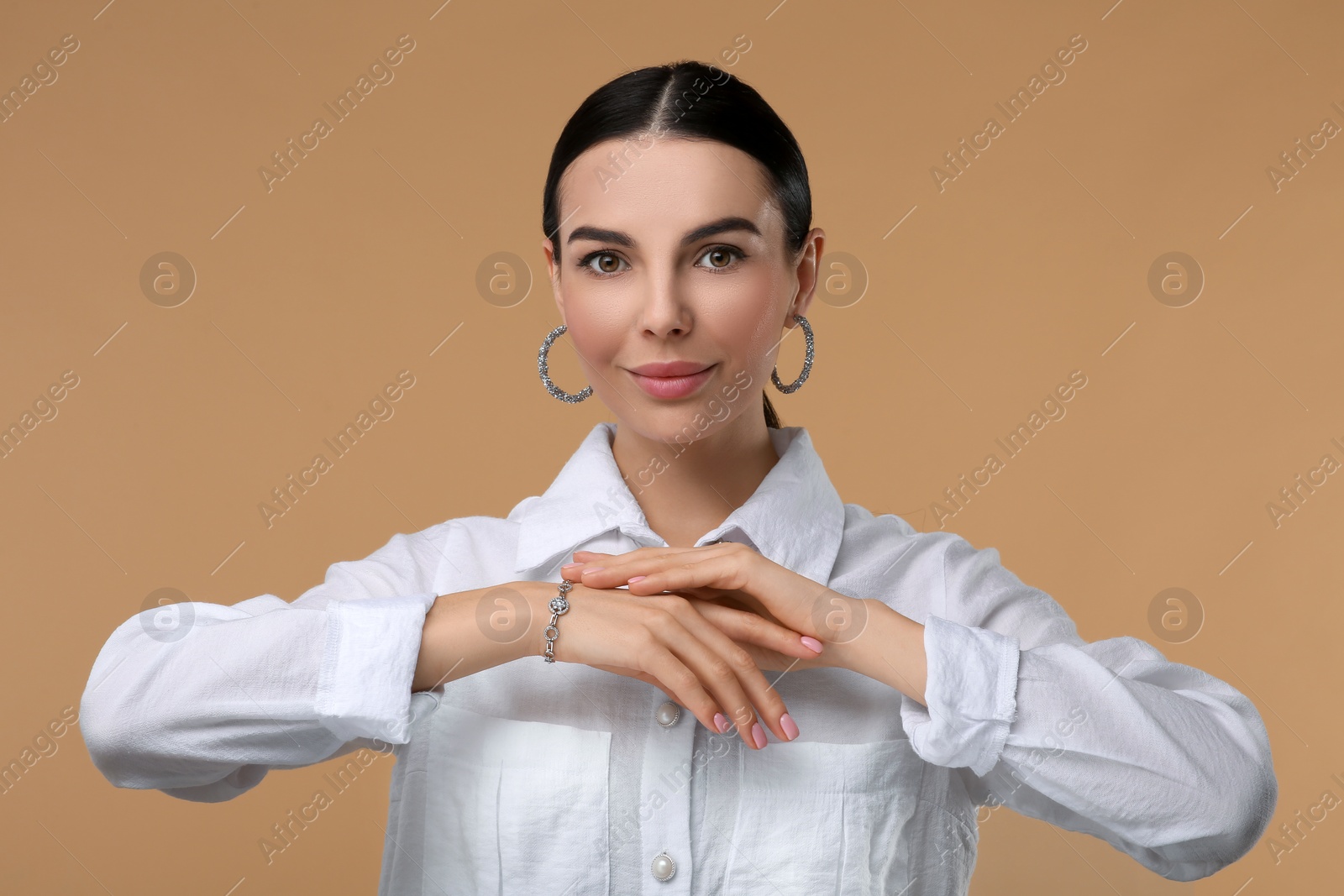 Photo of Young woman with elegant jewelry on beige background