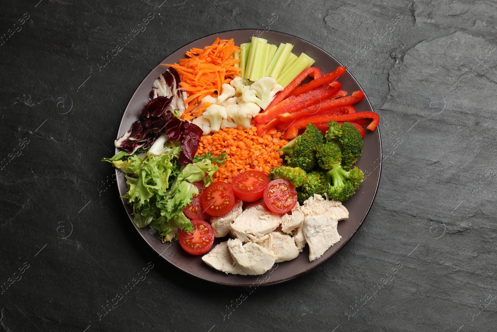 Photo of Balanced diet and healthy foods. Plate with different delicious products on black table, top view