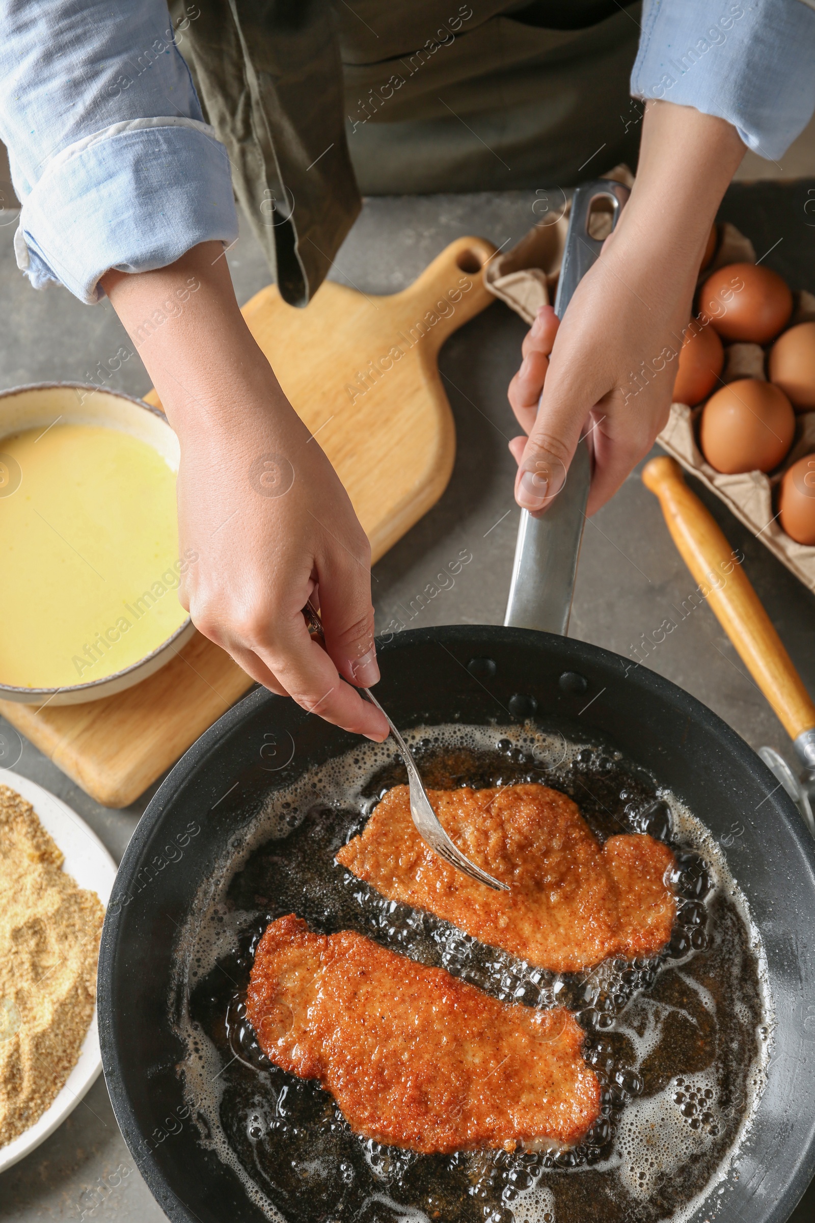 Photo of Woman cooking schnitzels in frying pan, top view