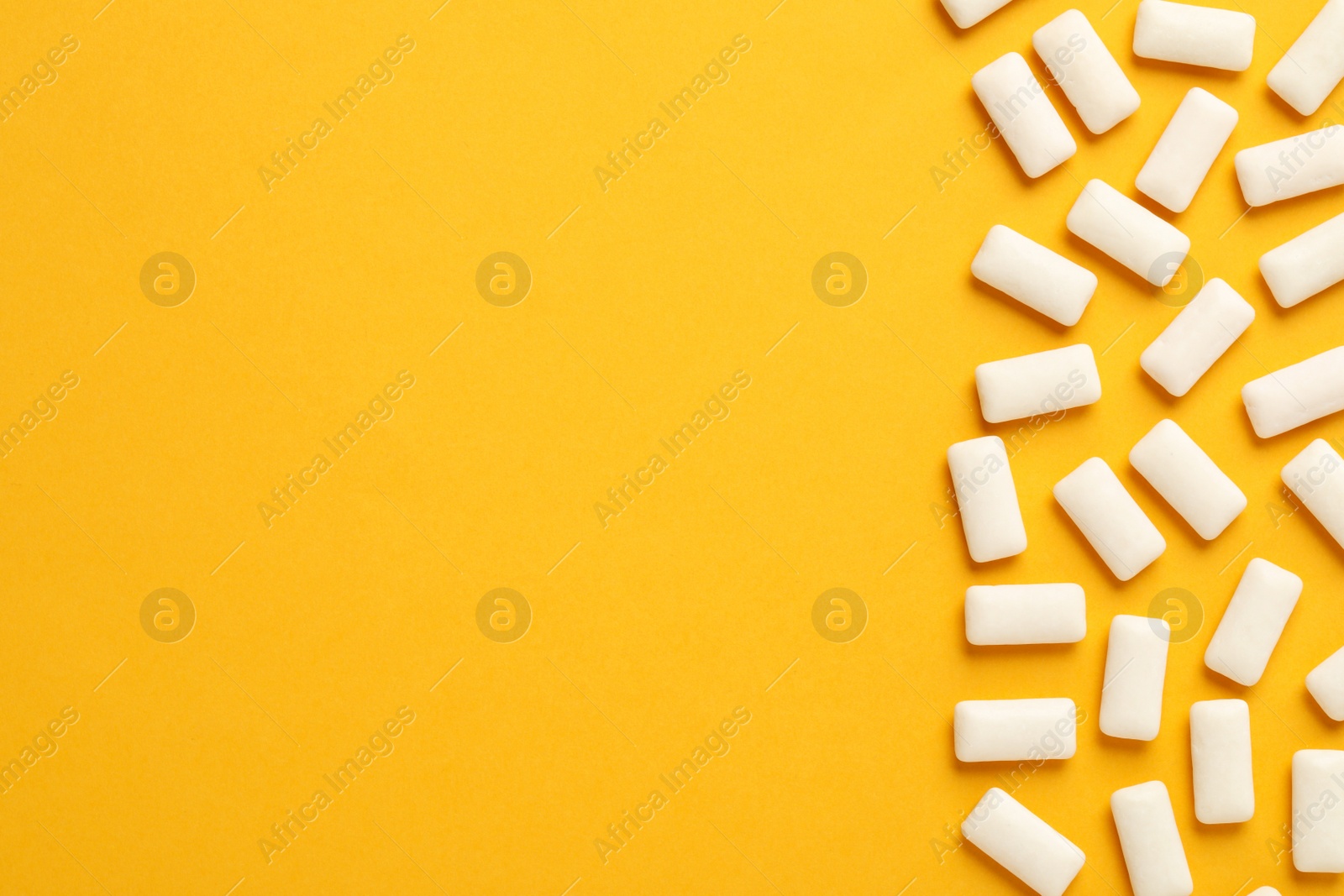 Photo of Many chewing gum pieces on orange background, flat lay. Space for text