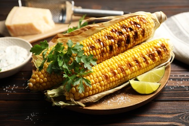 Photo of Delicious grilled corn cobs on wooden table