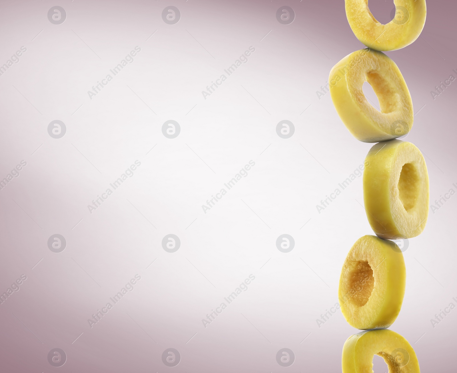 Image of Stacked slices of green olive on dusty greyish pink gradient background, space for text