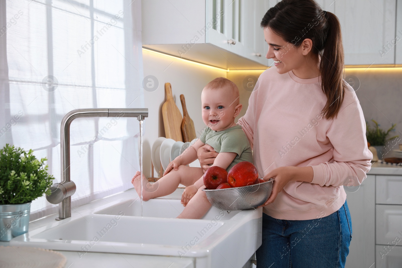 Photo of Mother and her cute little baby spending time together in kitchen